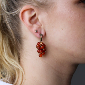 Collection of brown-red Carnelian stone orb dangle earrings with gold clasps.