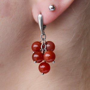 Carnelian earrings with brownish-red stones and silver hooks. 